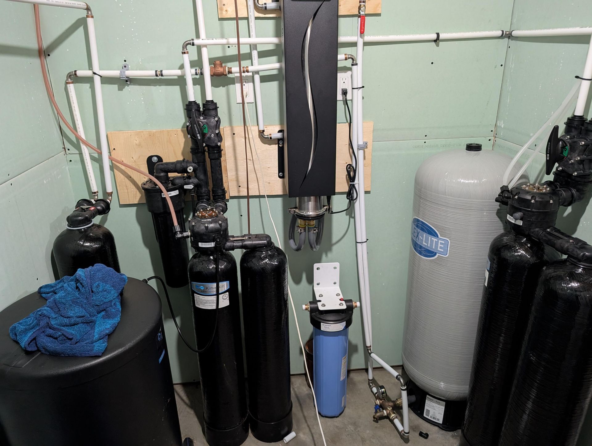Système de filtration d'eau dans un local technique avec plusieurs réservoirs, filtres et tuyaux.