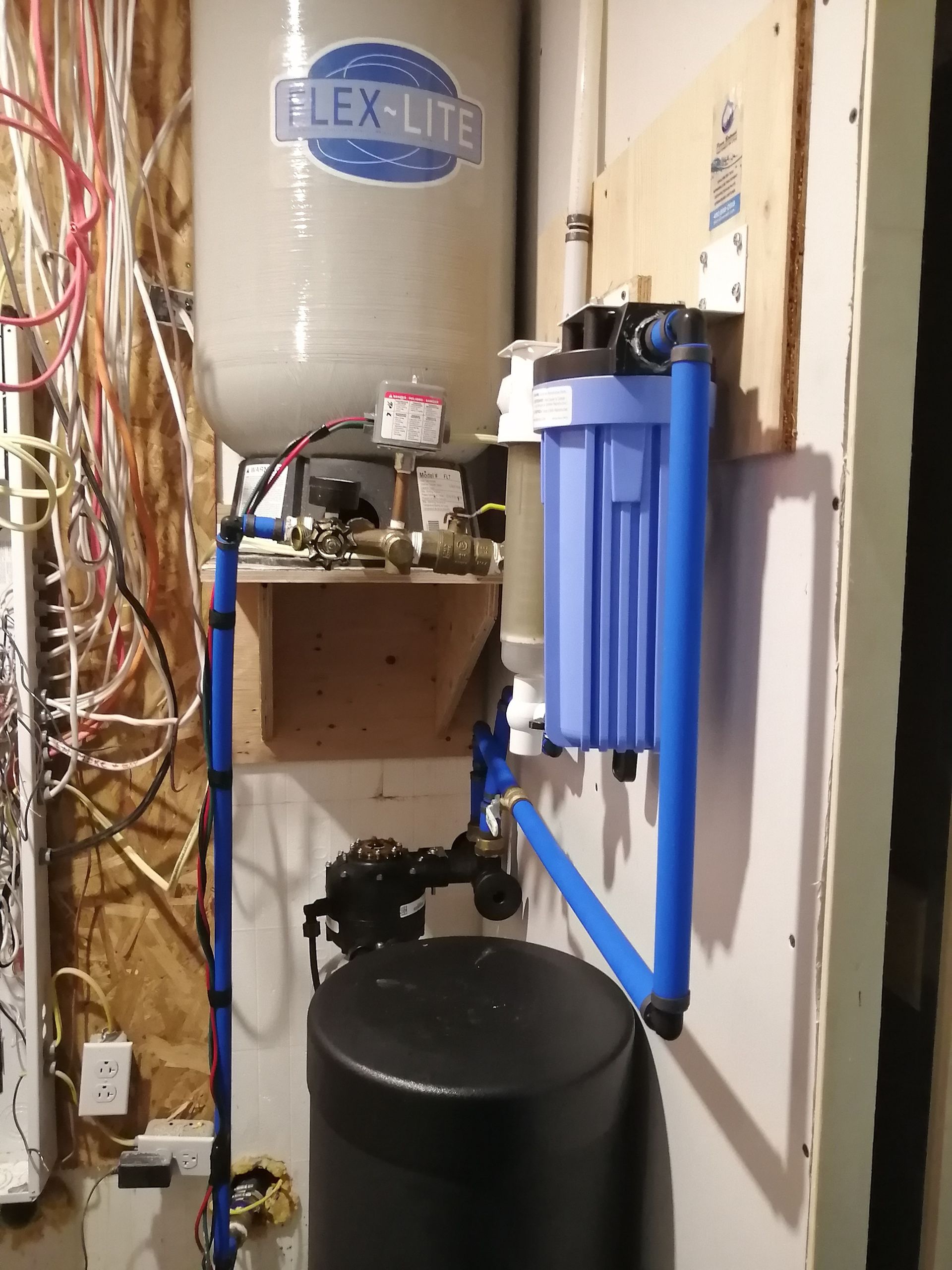 Système de filtration d'eau avec réservoir, filtre et plomberie, installé dans un local technique.