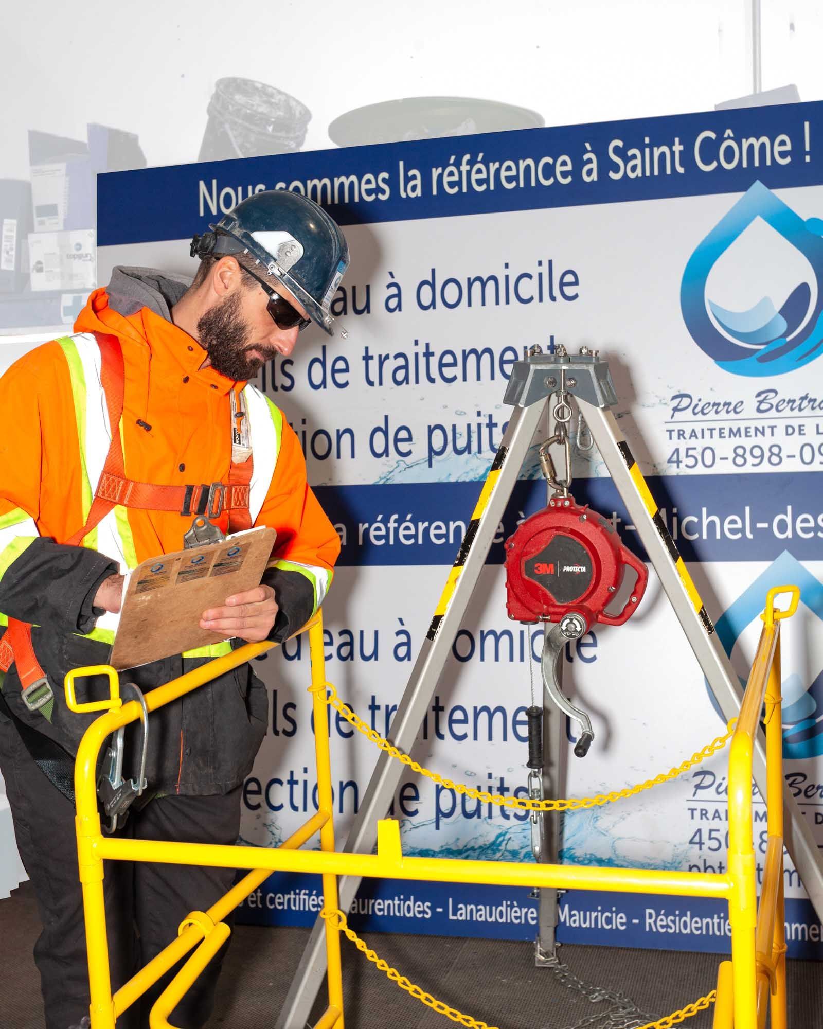 Homme en tenue de sécurité inspectant du matériel près d'un puits, Saint-Côme.