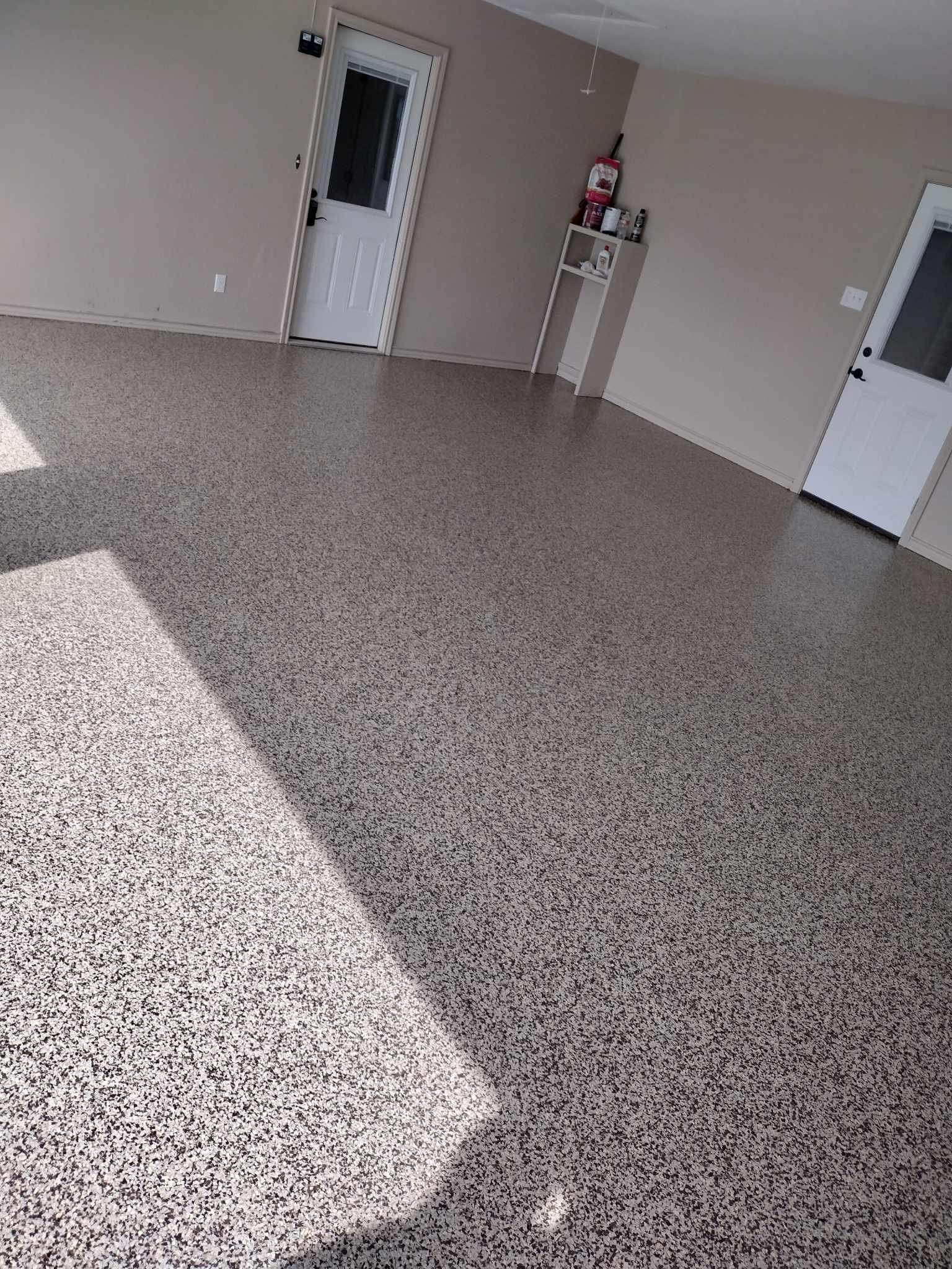 Empty room with speckled floor, white doors, and a small red fire extinguisher on the wall
