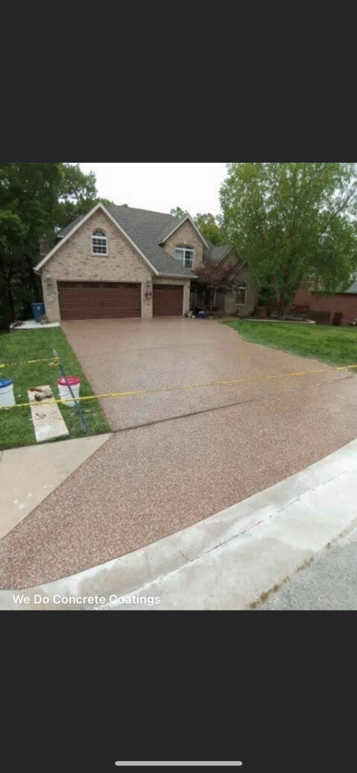 Suburban brick house with two-car garage, wide concrete driveway, and trees in front yard