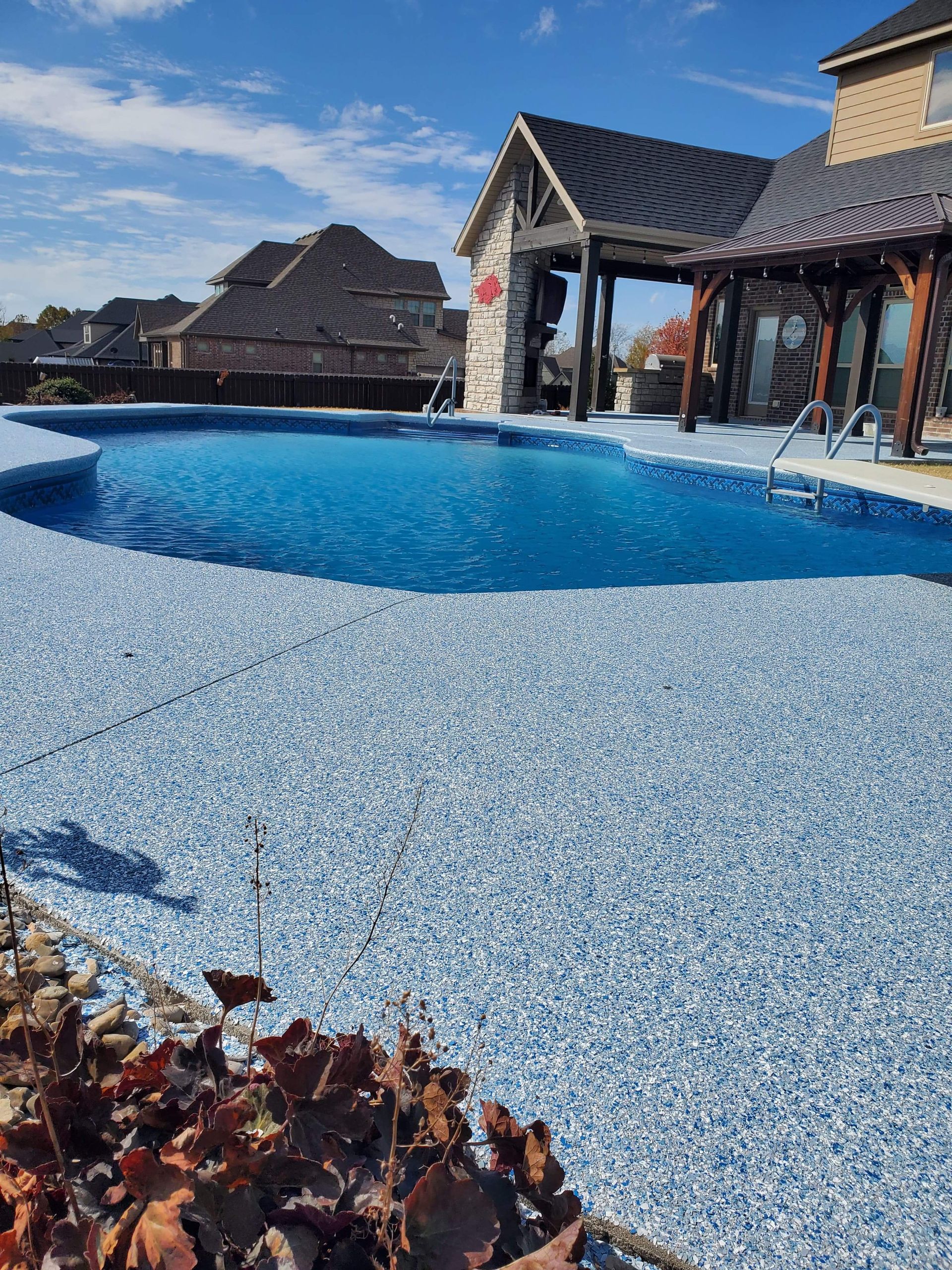 Blue swimming pool beside rustic thatched cabanas on a sunny day