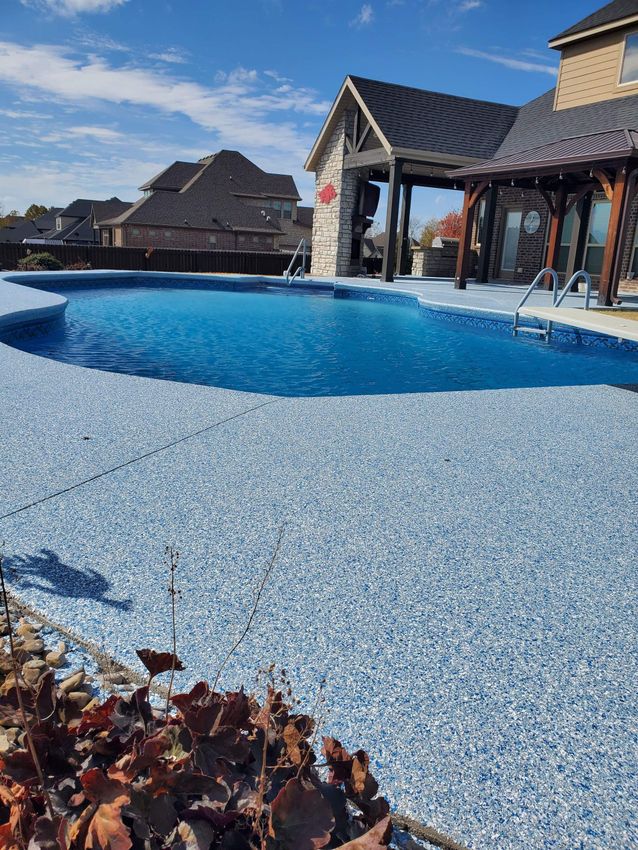Blue swimming pool beside rustic thatched cabanas on a sunny day