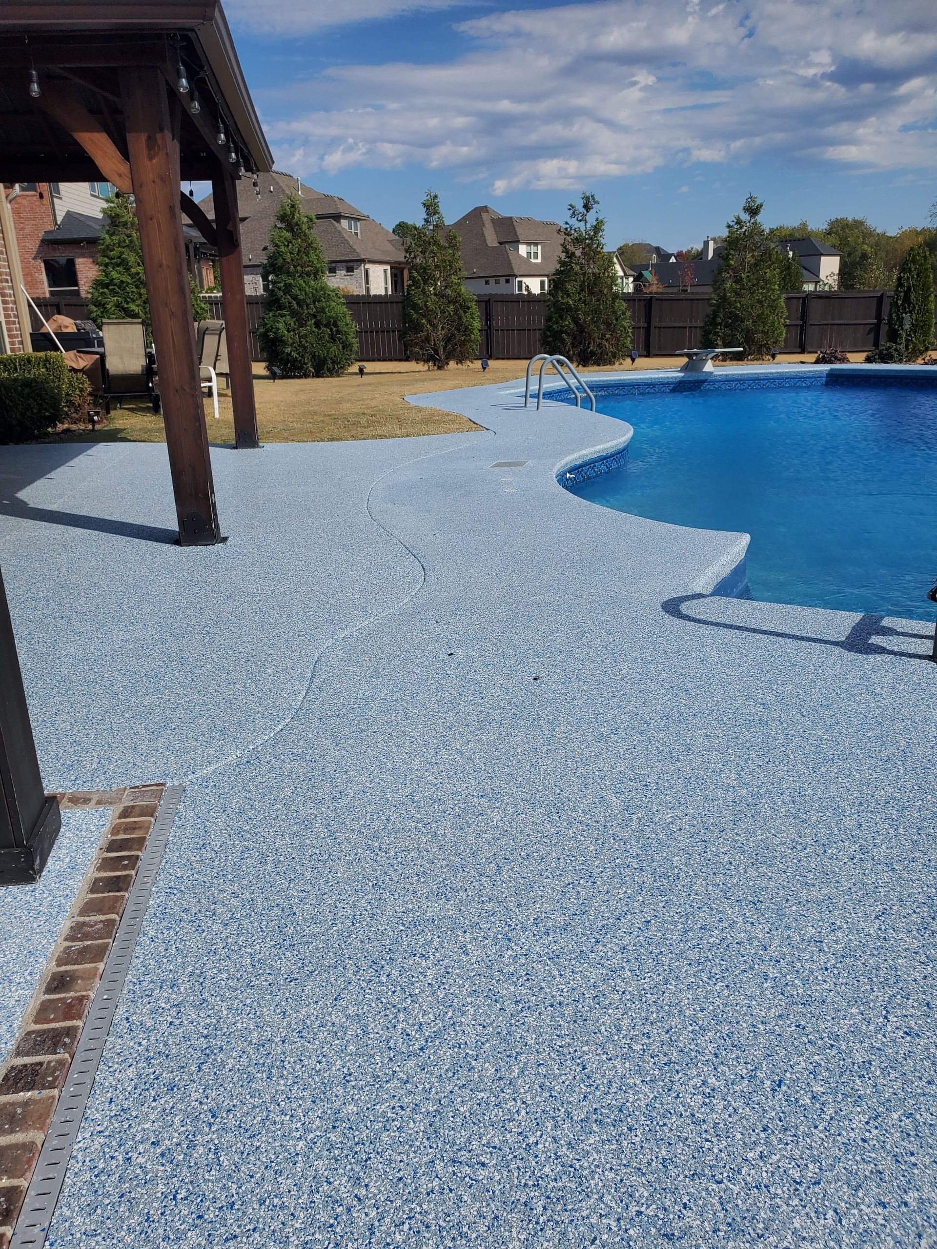 Poolside patio with blue mosaic paving, a swimming pool, and pergolas under a sunny sky