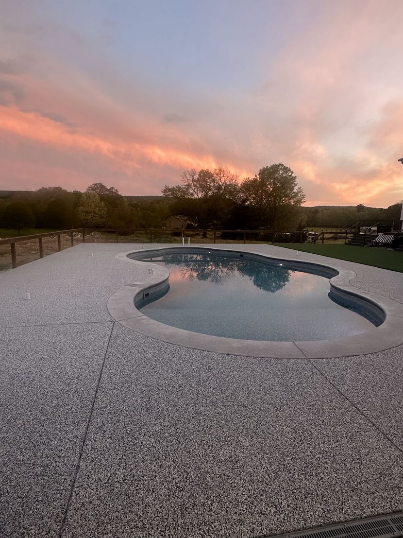 Backyard pool at sunset with pink clouds reflecting in calm water