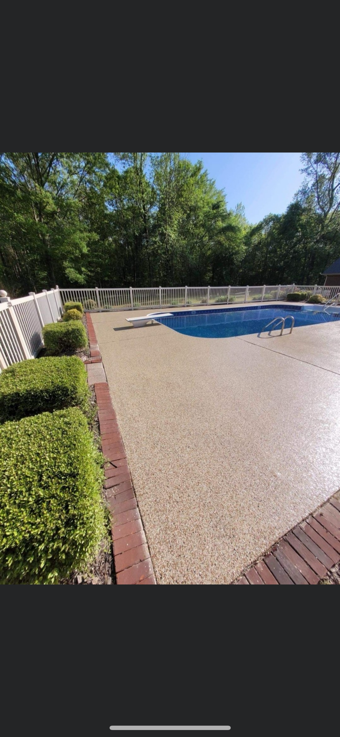 Backyard pool with blue water, brick patio, hedges, and trees in bright sunlight