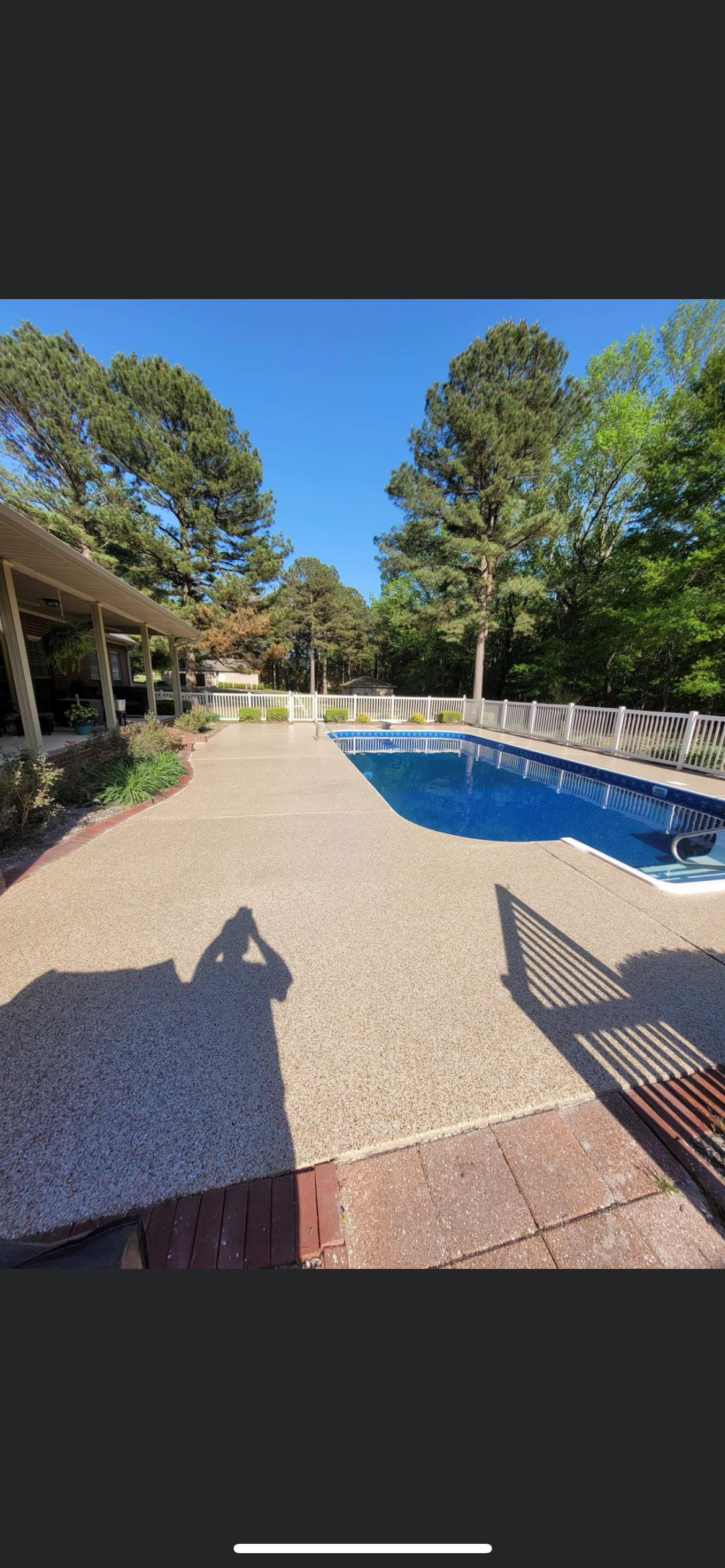 Backyard pool with blue water, gravel patio, lounge chair, and trees under a clear sky