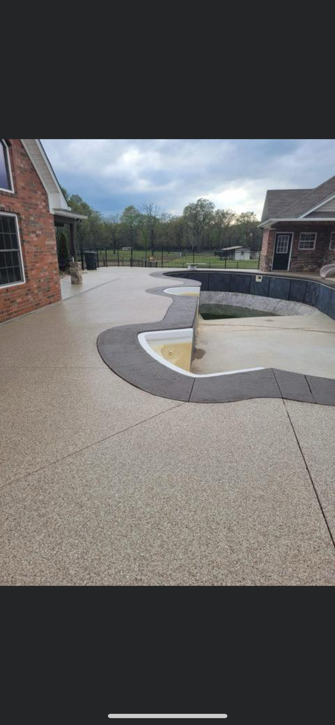 Outdoor school courtyard with curved concrete seating and a small yellow fountain area between brick buildings