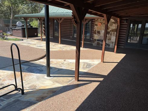 Covered brick walkway with benches and metal posts beside a building in sunlight