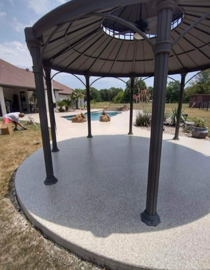 Circular shaded pavilion with dark columns on a white patio in a landscaped courtyard