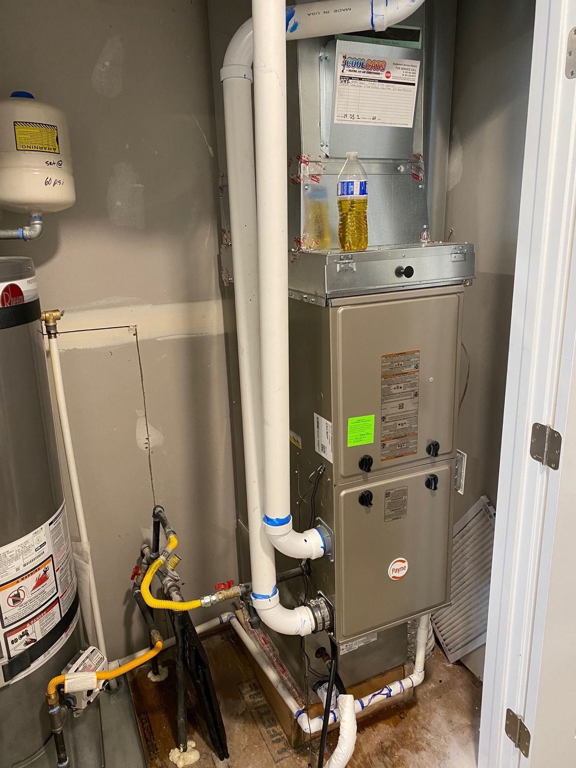 A stainless steel heater is sitting in a room next to a water heater.