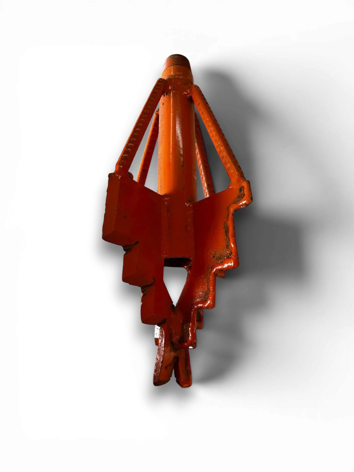 Adorno colgante u objeto decorativo de color rojo anaranjado sobre un fondo blanco, que proyecta una sombra suave.
