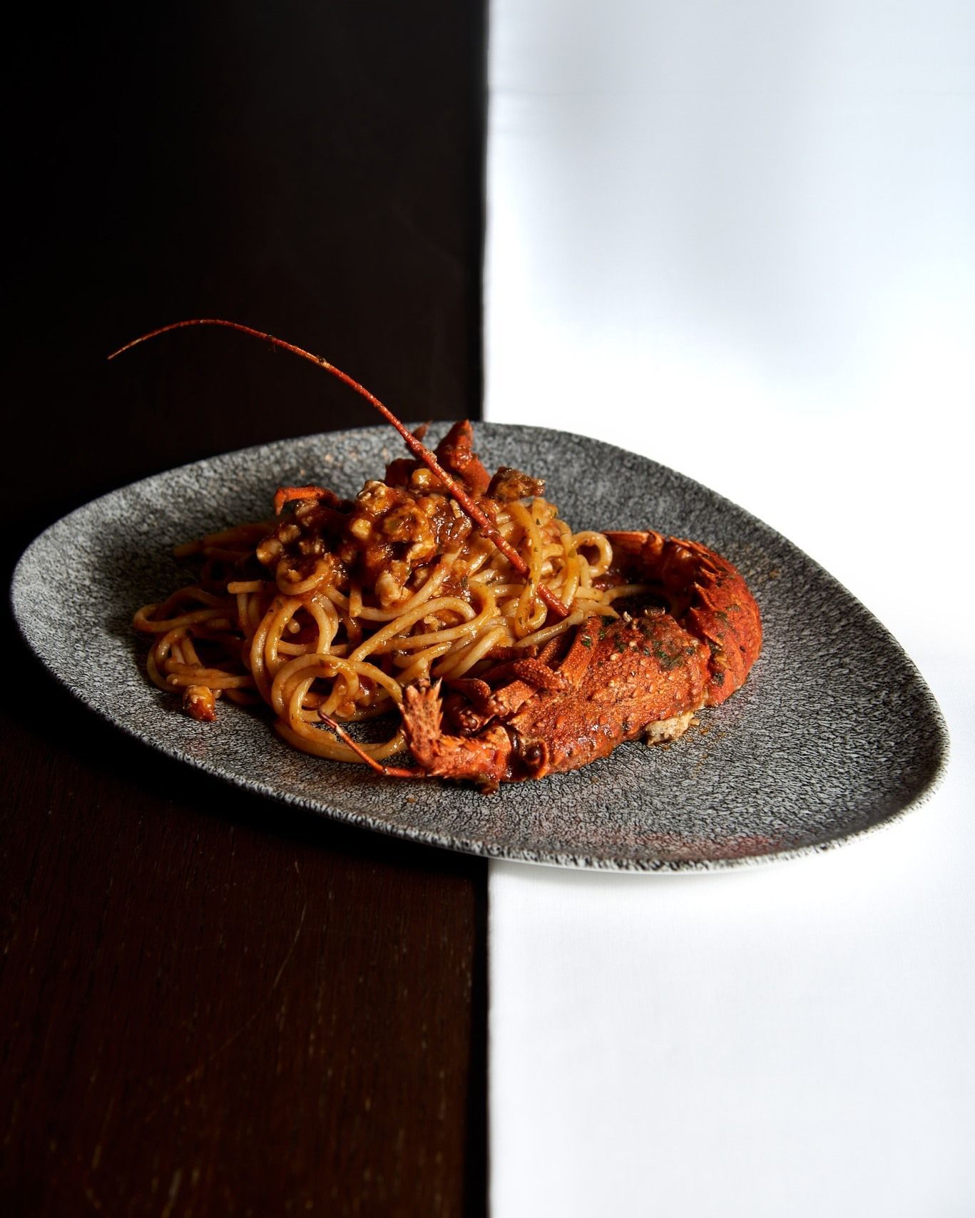 Un piatto di spaghetti e aragosta su un tavolo bianco e nero.