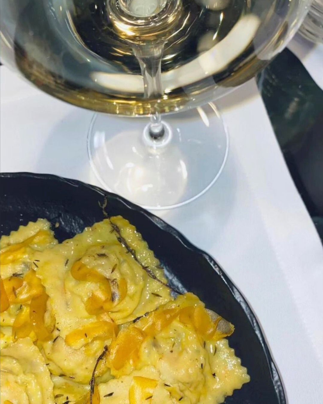 Un piatto di ravioli accanto a un bicchiere di vino