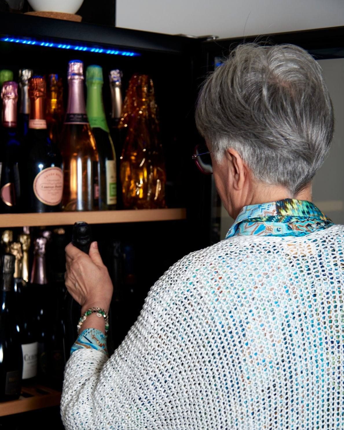 Una donna sta guardando le bottiglie di vino su uno scaffale.