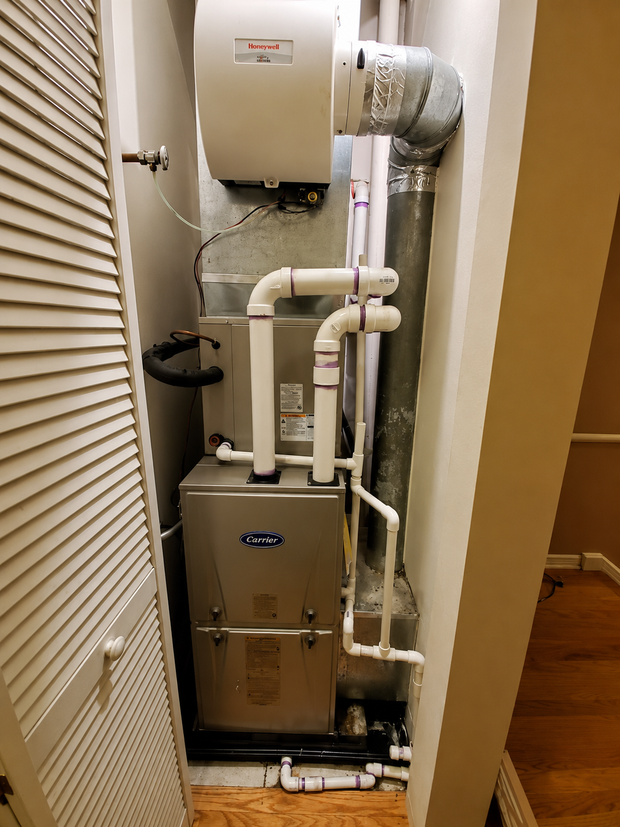 Home HVAC furnace and ductwork in a narrow utility closet.