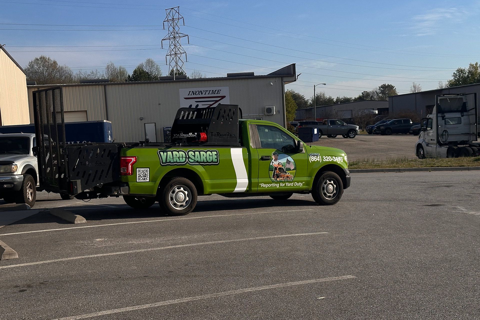 Green pickup truck with company branding parked in a lot on a sunny day.