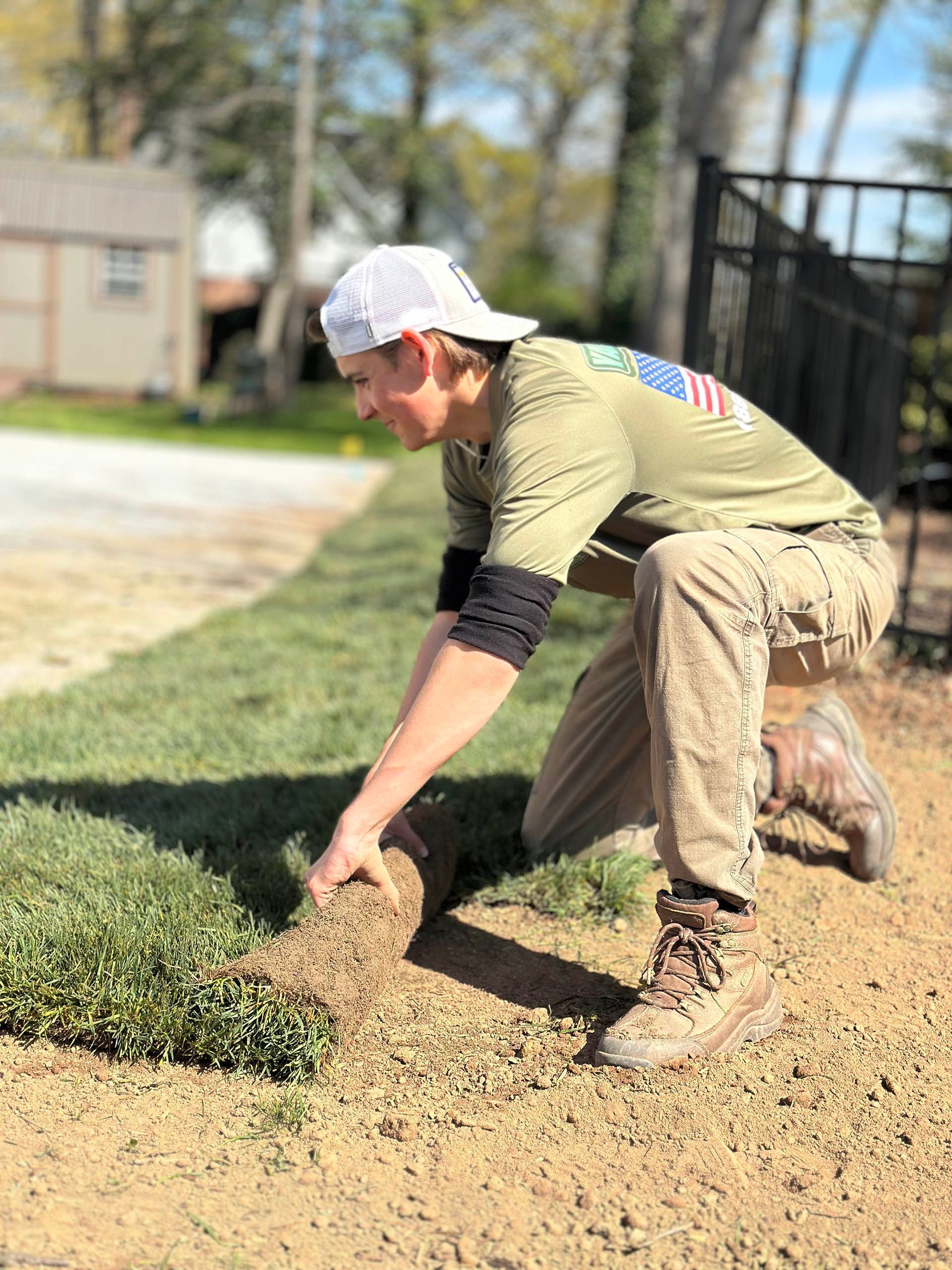 Hand on a red lawn mower pushing through a pile of dry brown leaves outdoors