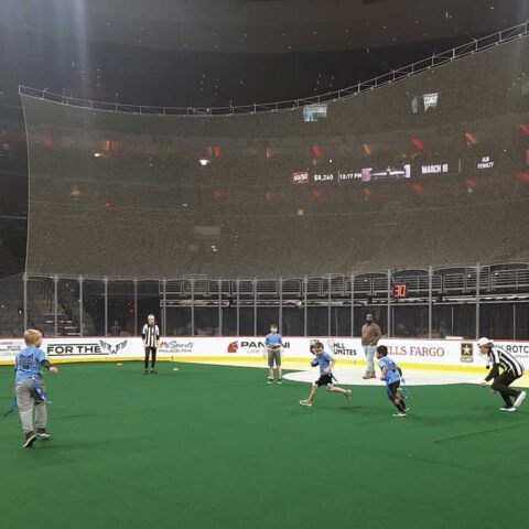 Football game on green turf, with players in blue and black jerseys near the goal.