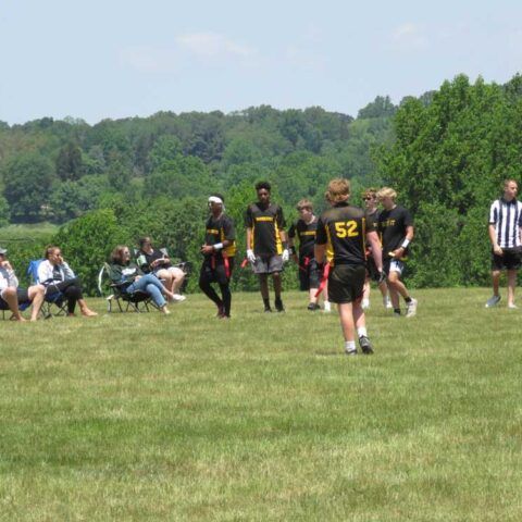 Youth football players on a grassy field, with one wearing a black jersey numbered 52.