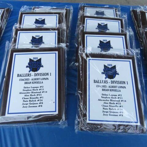 Football division award plaques in plastic sleeves on a blue tablecloth