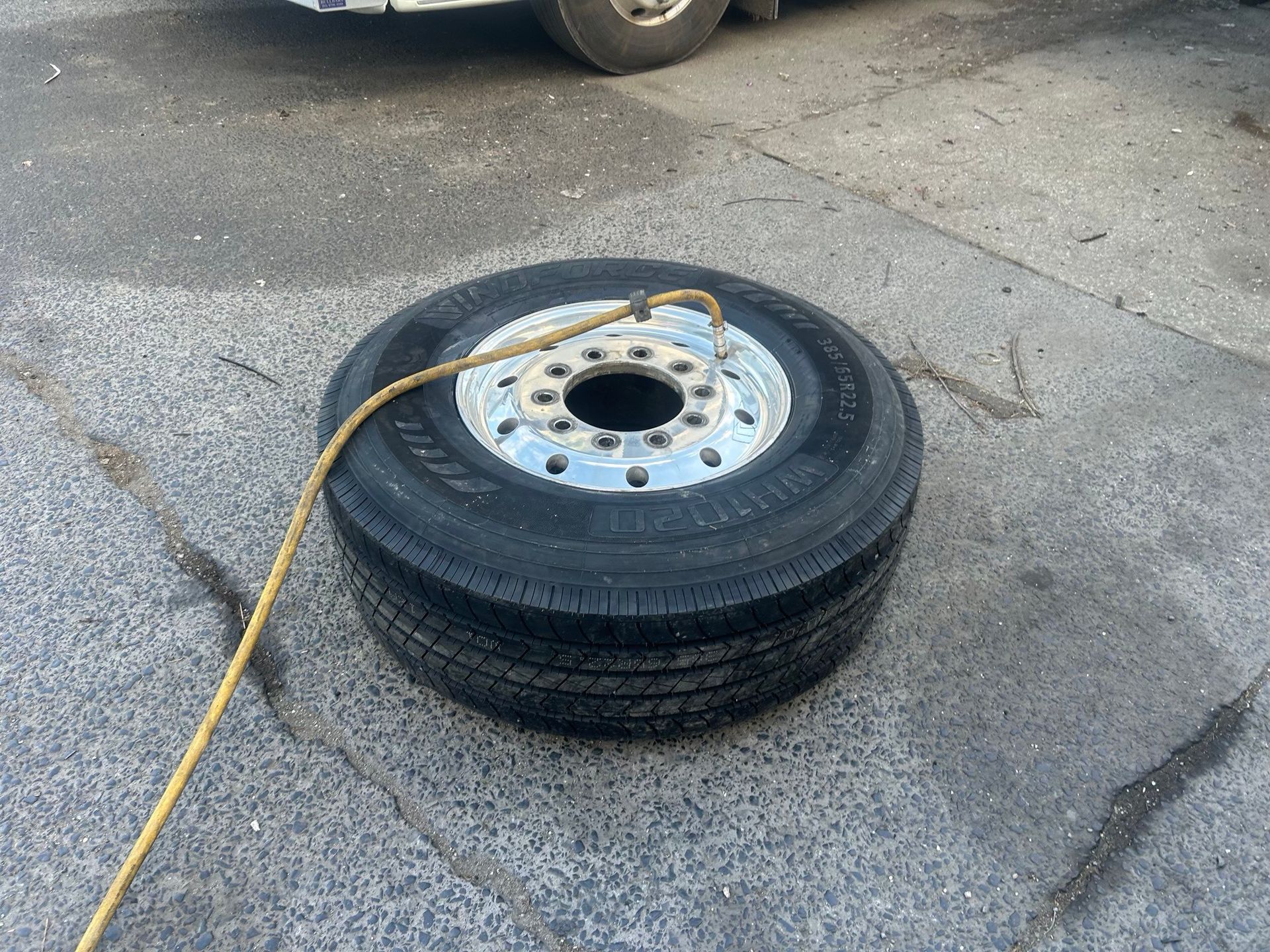 Stacked tire and wheel rims on pavement with a yellow strap draped across them