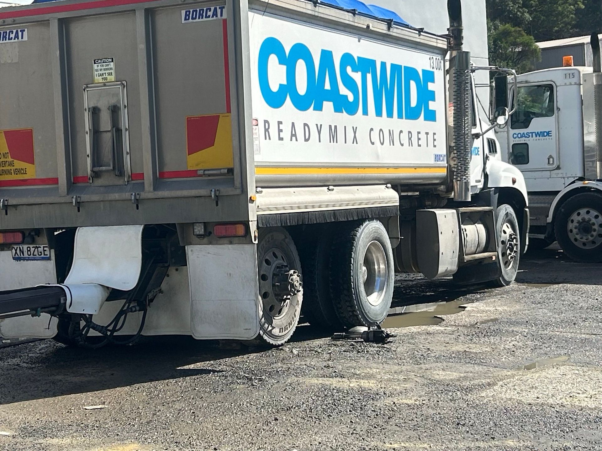 Coastwide concrete truck parked on a gravel lot, rear view with blue-and-white branding