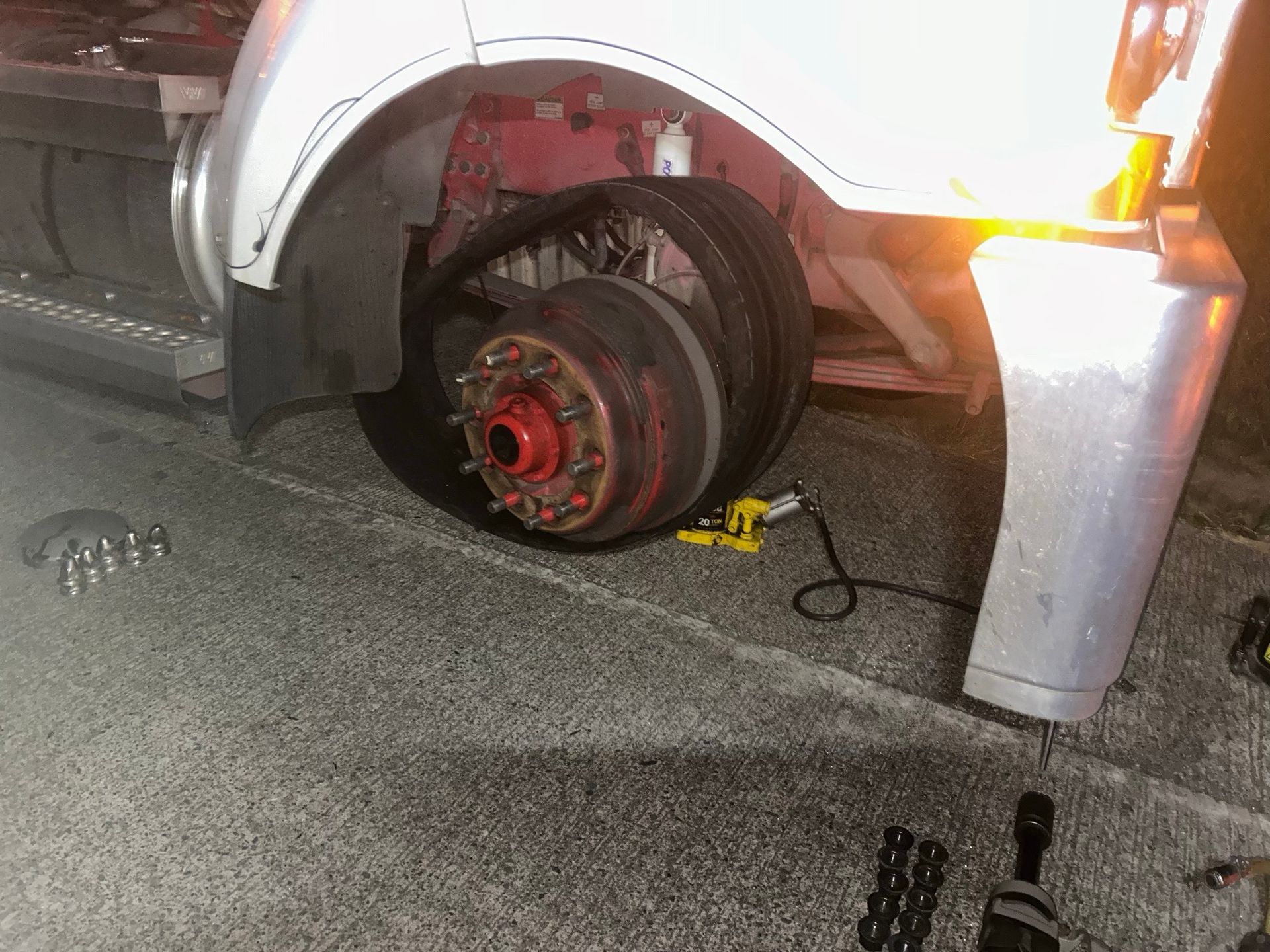 Truck with a detached front wheel and damaged brake assembly on the roadside at night