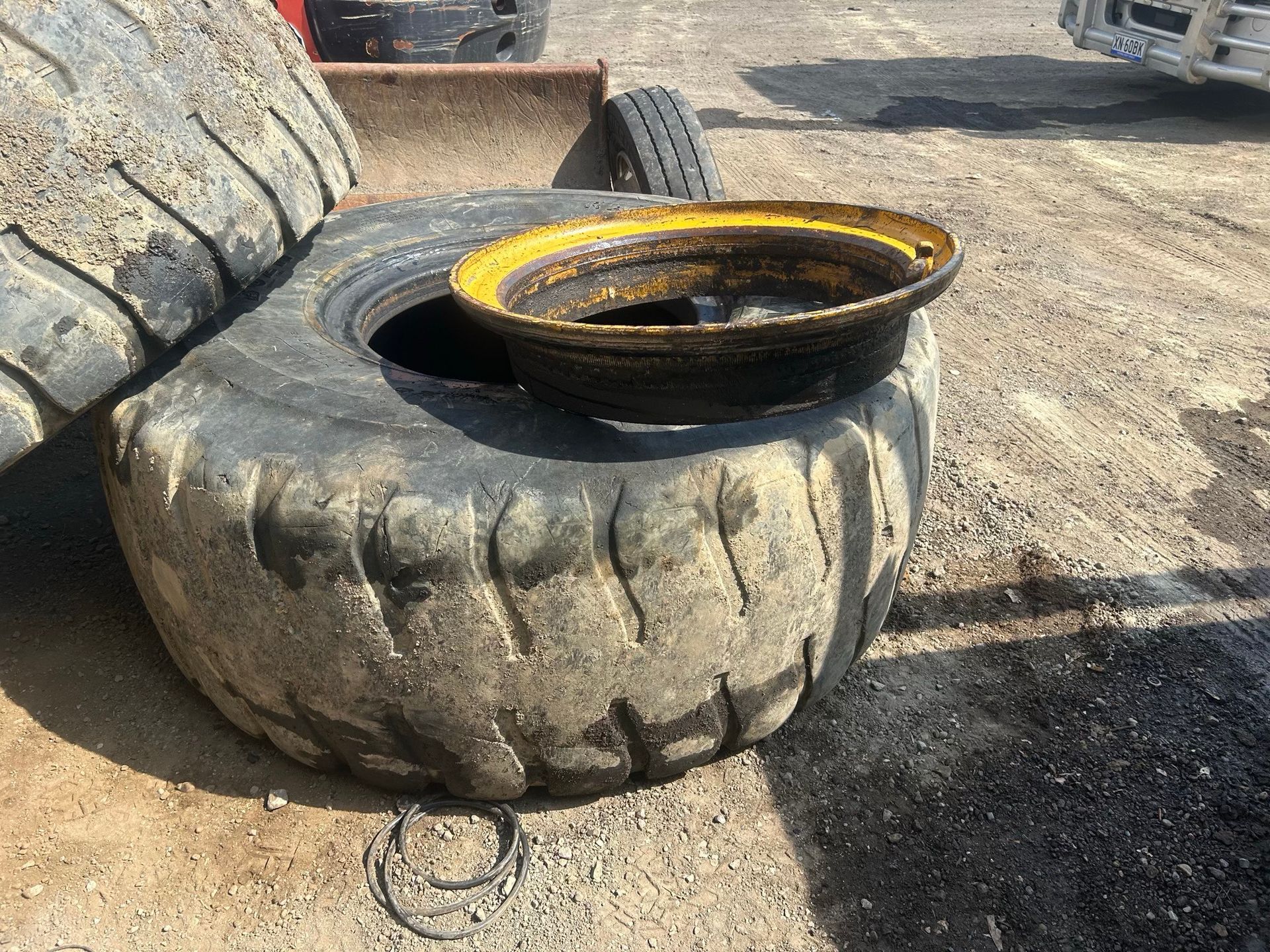 Two large worn tires stacked outdoors with a black and yellow metal basin on top
