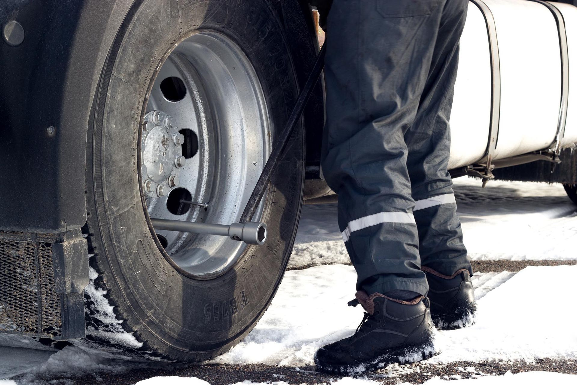 Truck tire being checked with a wrench in a snowy roadside scene