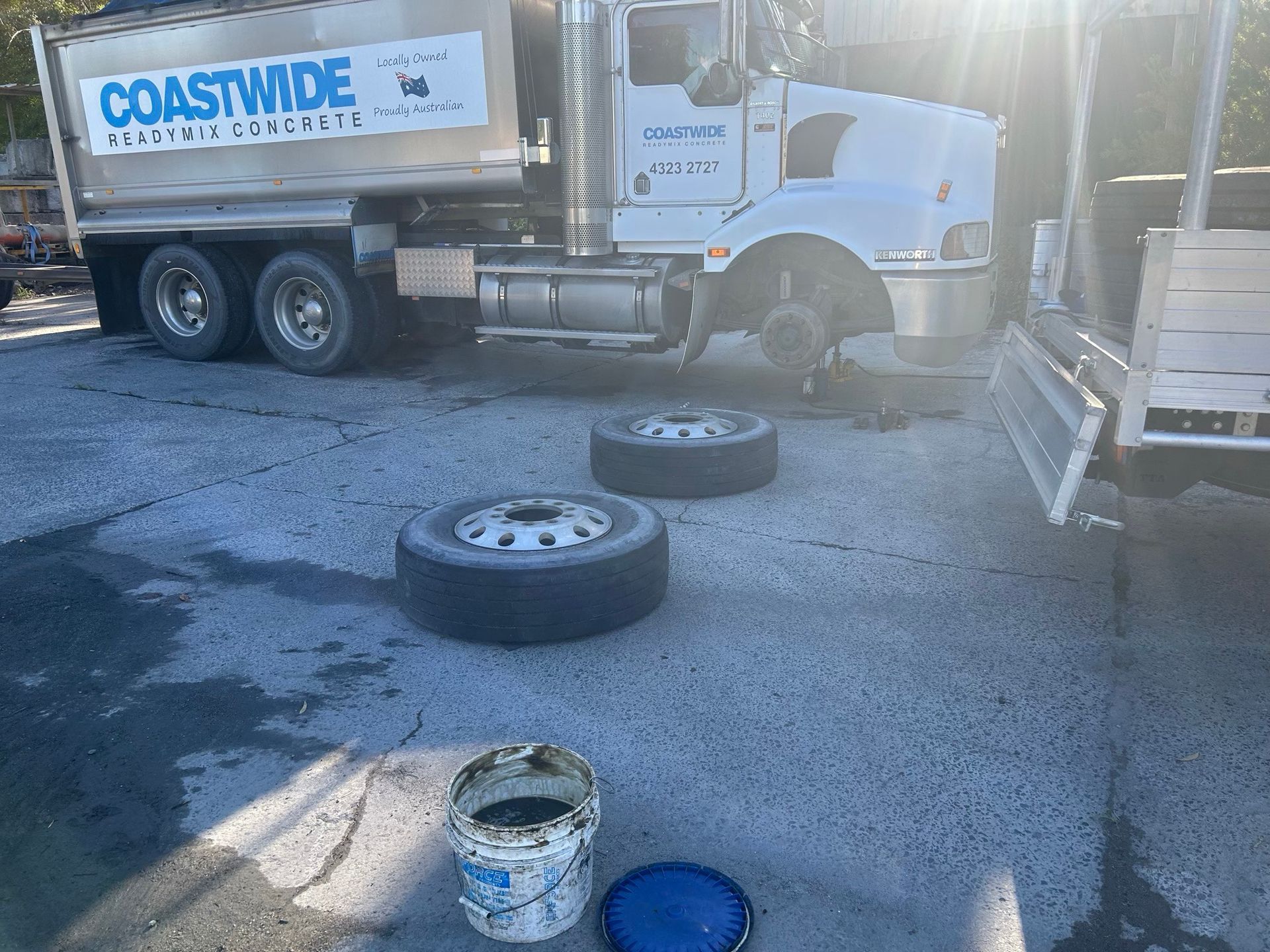 Coastwise truck at loading area with two detached tires and a bucket on the ground