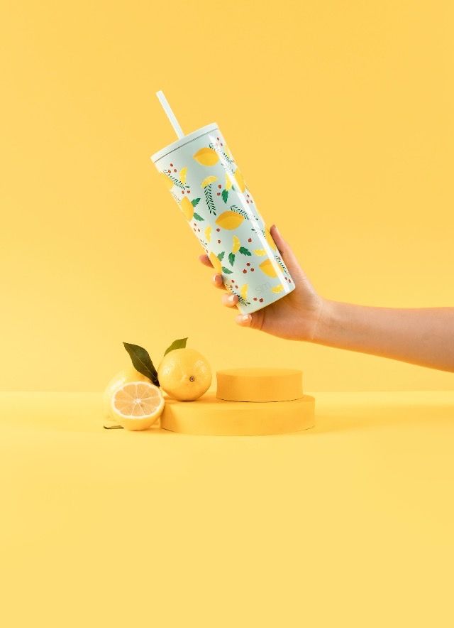 A person is holding a stainless steel tumbler with a straw.