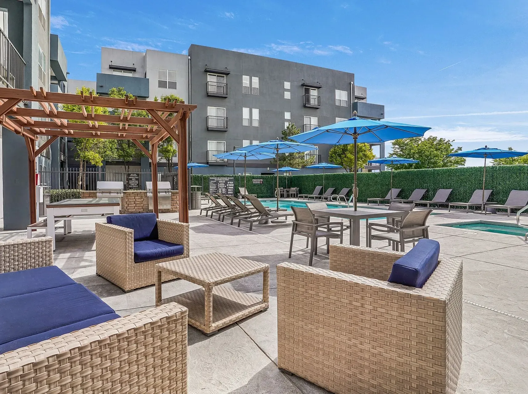 Poolside lounge area with seating, umbrellas, and grills at Solaire, offering apartments in Albuquerque, NM.