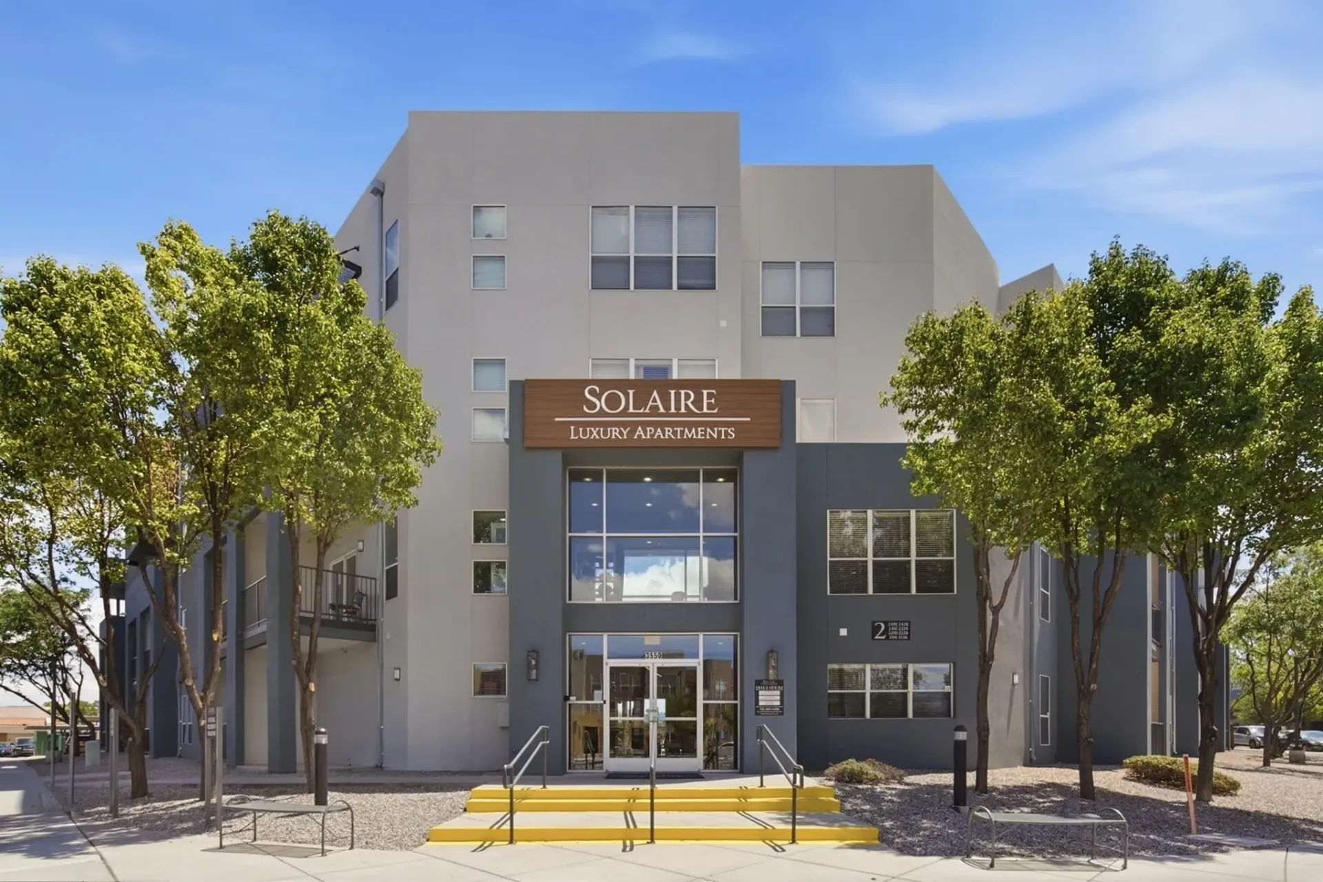 Solaire Luxury Apartments building exterior with trees and entrance.
