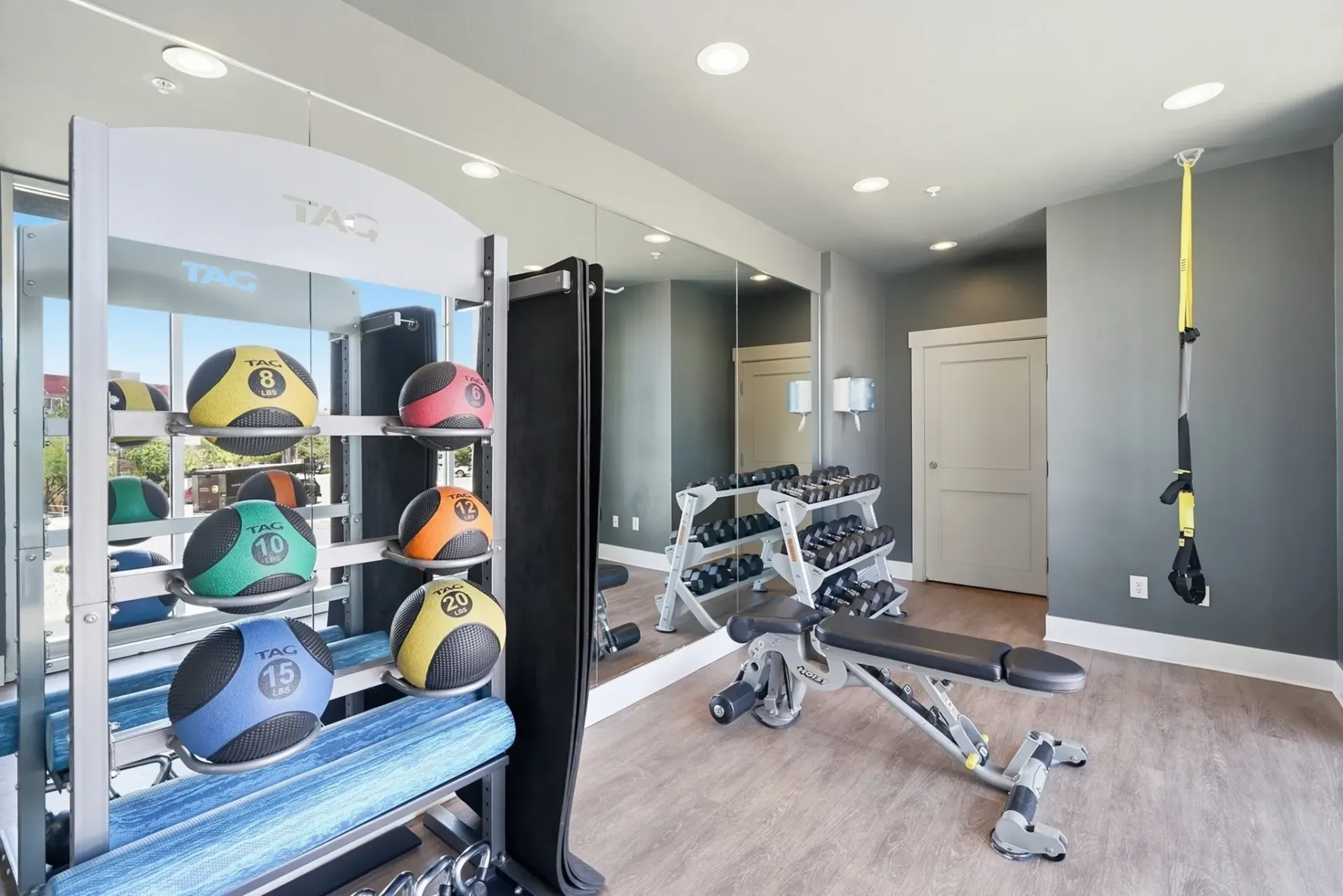 Fitness center with medicine balls, dumbbells, and workout bench at Solaire, offering apartments in Albuquerque, NM.