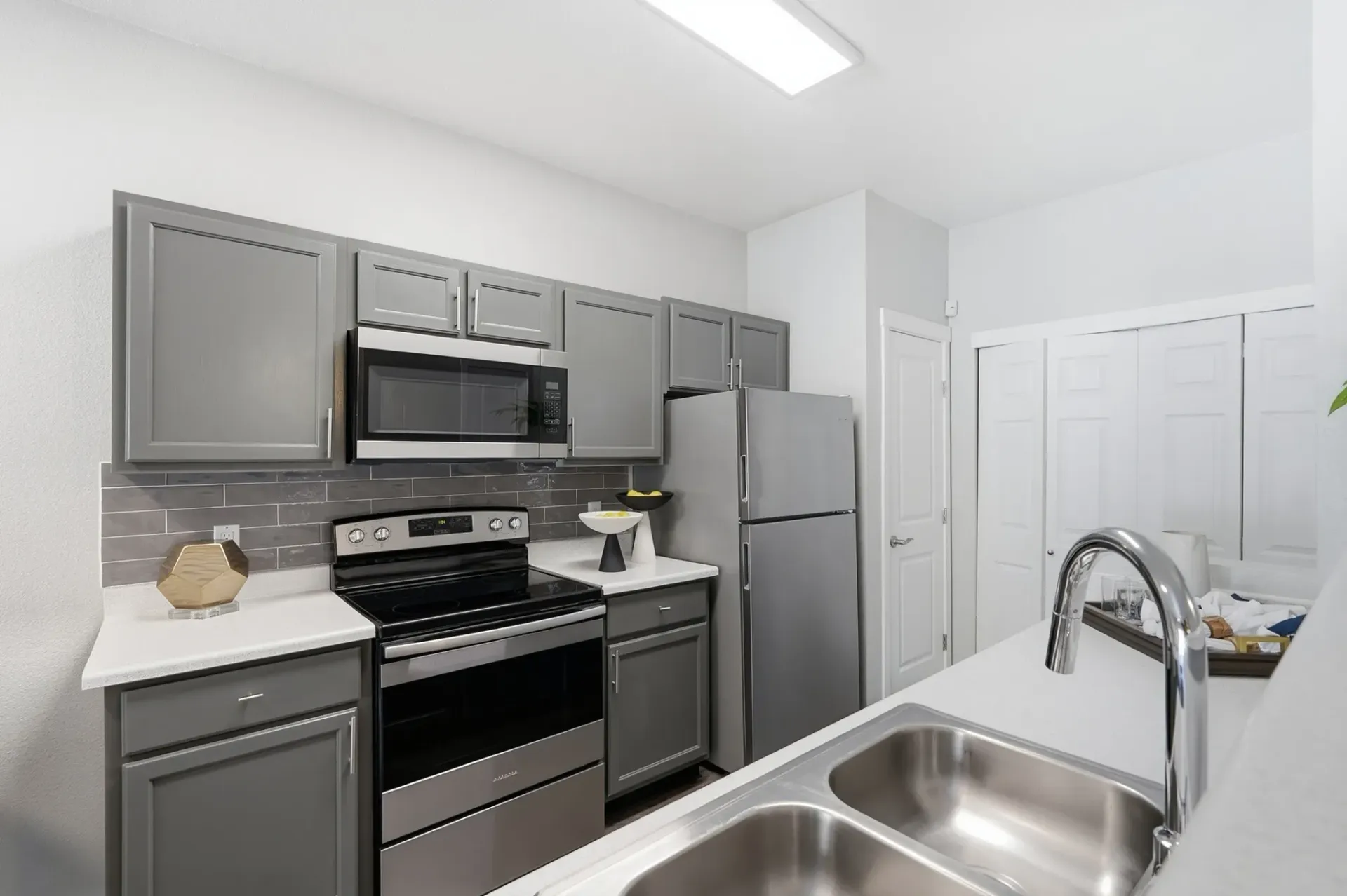 Modern kitchen with gray cabinets, stainless steel appliances, and a double sink at Solaire, offering apartments in Albuquerque, NM.