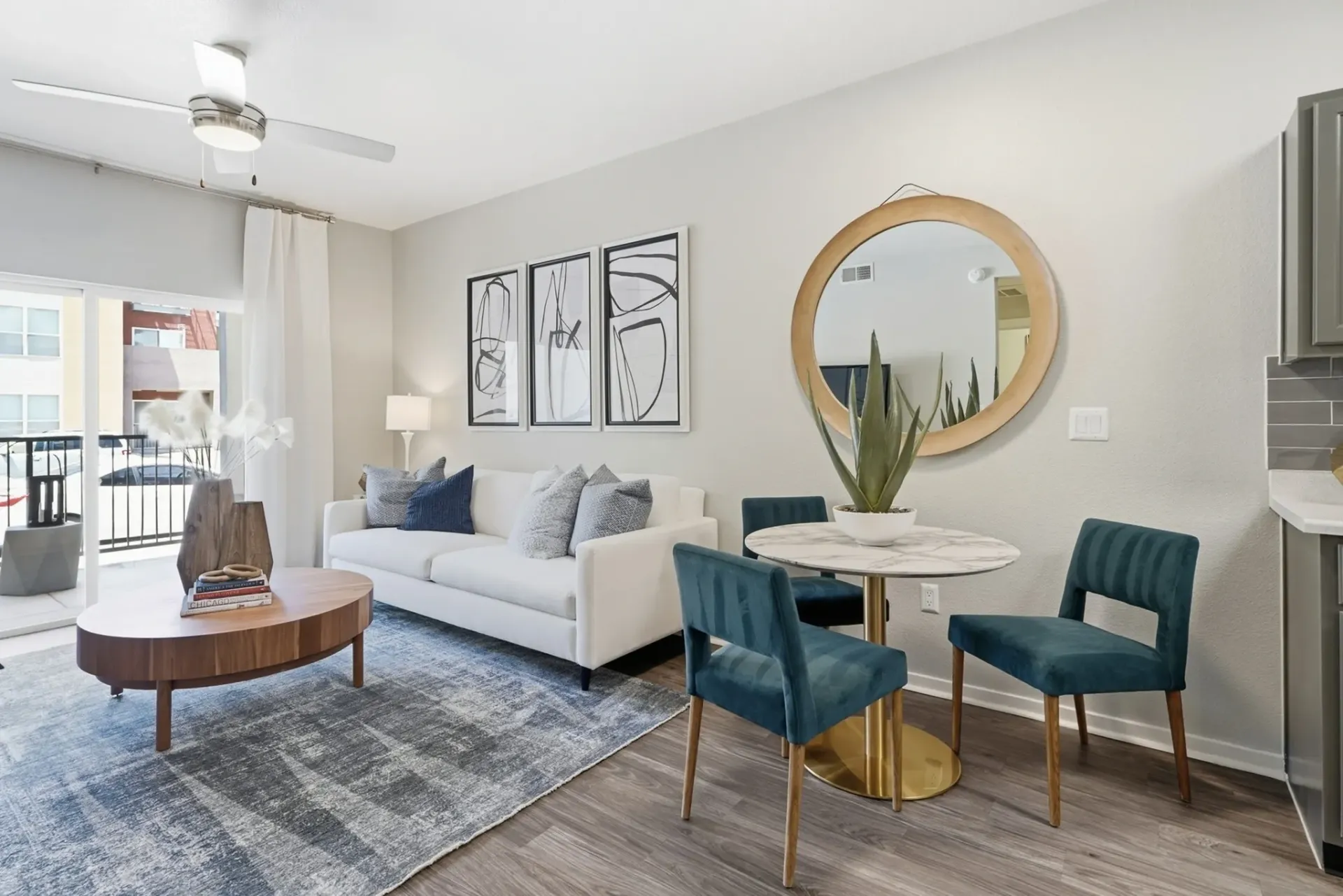 Modern living and dining area with white sofa, blue chairs, and marble-top table at Solaire, offering apartments in Albuquerque, NM.