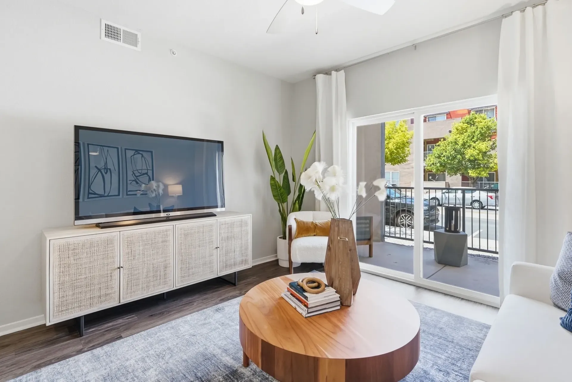 Living room with a TV, coffee table, and a sliding glass door to a patio at Solaire, offering apartments in Albuquerque, NM.