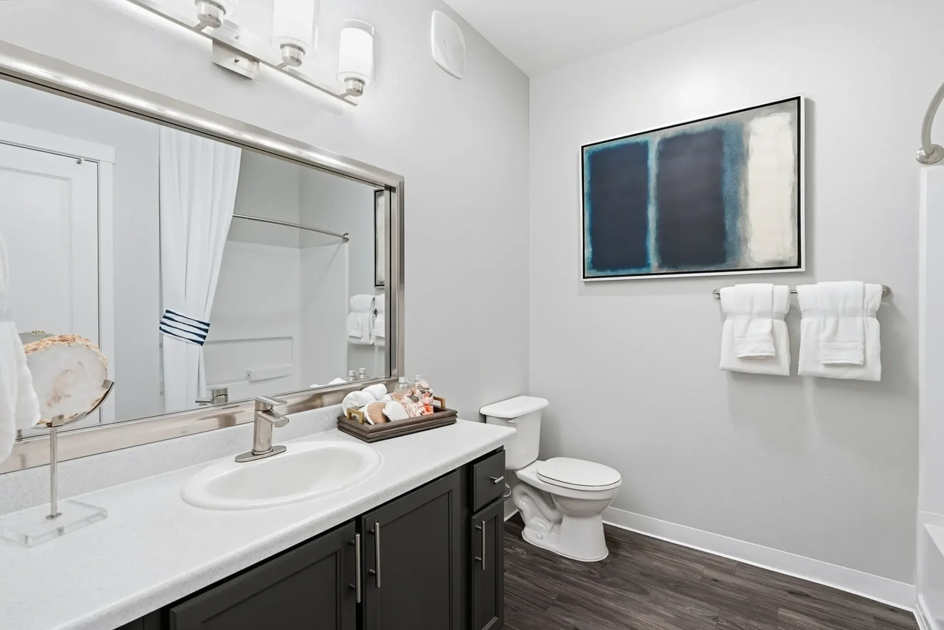 Modern bathroom with a vanity, sink, large mirror, toilet, and shower at Solaire, offering apartments in Albuquerque, NM.