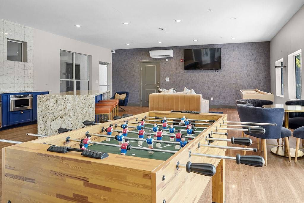 Interior of a modern apartment community lounge with a foosball table, seating, and a TV at Solaire Luxury Apartments, offering apartments in Albuquerque, NM.