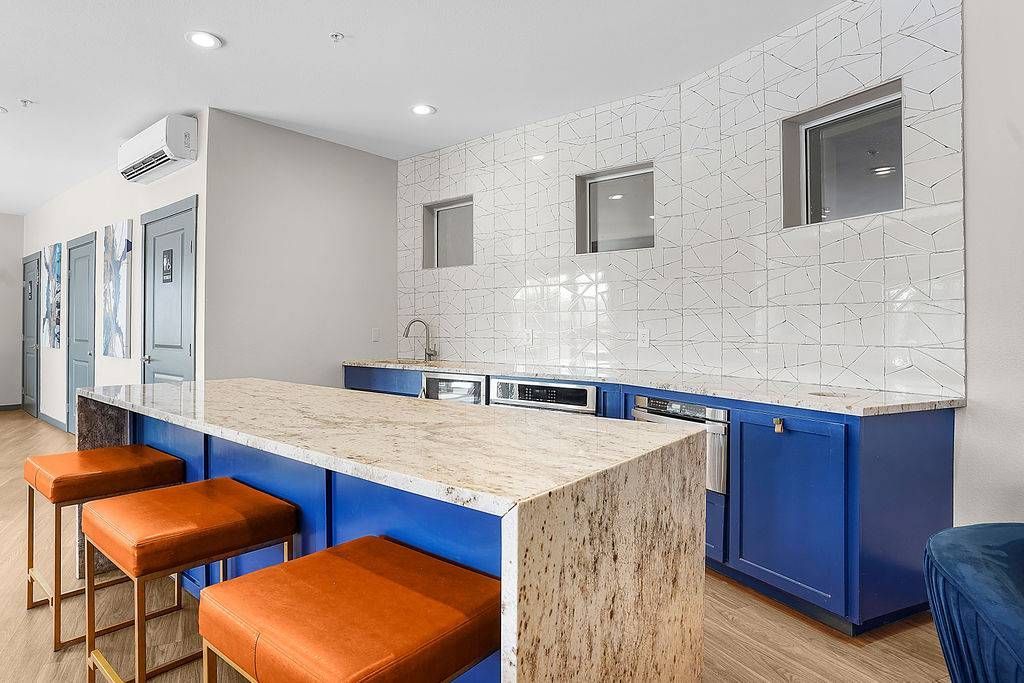 Modern communal kitchenette with marble island, blue cabinets, and orange bar stools at Solaire Luxury Apartments, offering apartments in Albuquerque, NM.