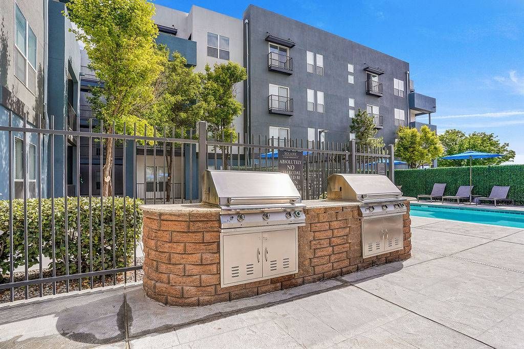 Outdoor pool area with built-in grills and lounge chairs beside a modern apartment building at Solaire Luxury Apartments, offering Albuquerque apartments for rent.