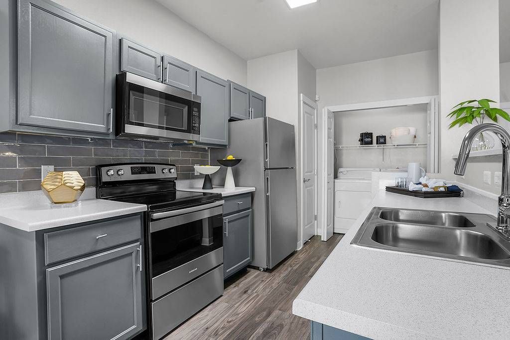 Modern apartment kitchen with gray cabinets, stainless steel appliances, and a double sink at Solaire Luxury Apartments, offering Albuquerque apartments for rent.