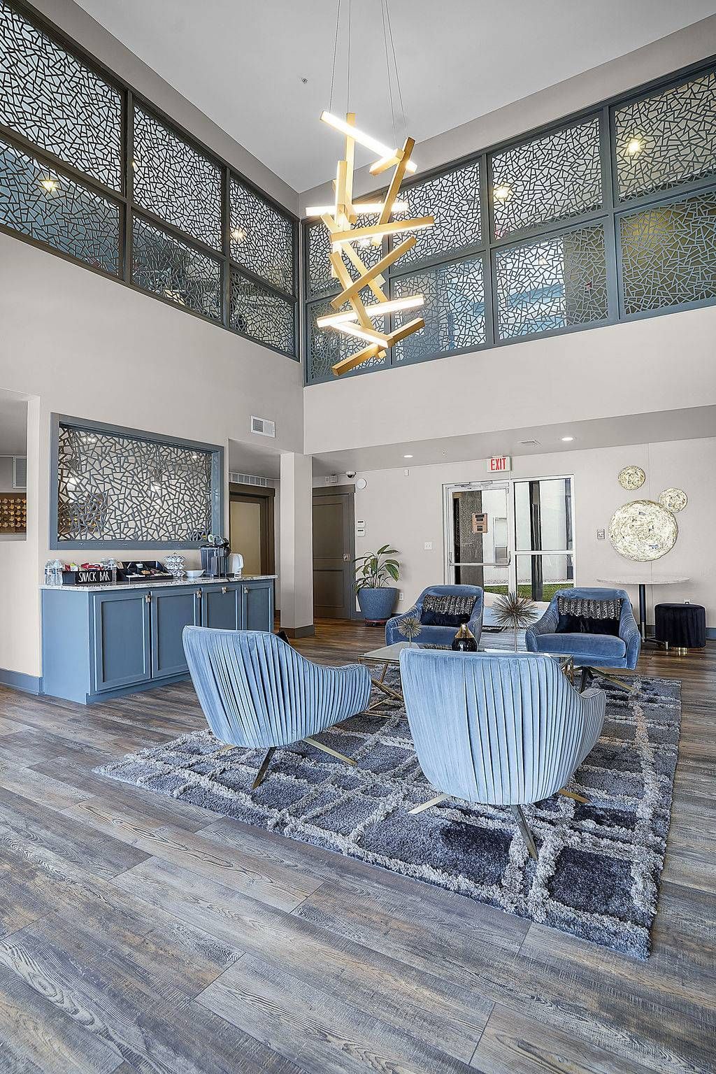 Modern apartment lobby with blue lounge seating, decorative screens, and a chandelier at Solaire Luxury Apartments, offering apartments for rent in Albuquerque, NM.