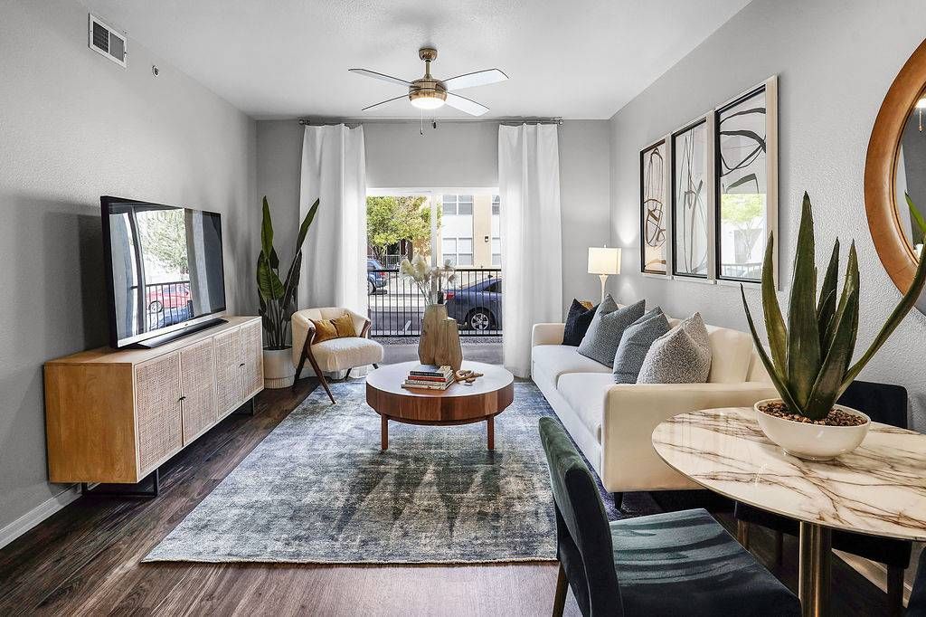 Modern apartment living room with white sofa, coffee table, TV, and potted plants at Solaire Luxury Apartments, offering Albuquerque apartments for rent.