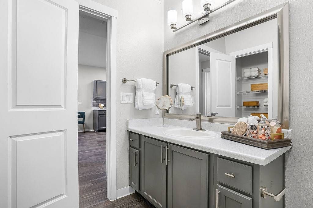 Bathroom vanity with sink, large mirror, and organized cabinet with towels at Solaire Luxury Apartments, offering Albuquerque apartments for rent.