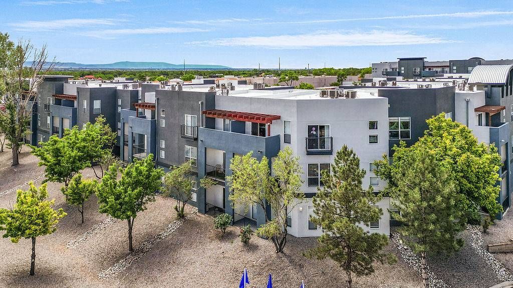 Aerial view of a modern apartment complex at Solaire Luxury Apartments, featuring white and gray buildings, balconies, and trees, offering apartments in Albuquerque, NM.