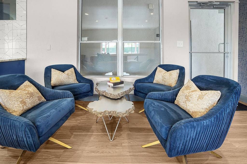 Four blue velvet lounge chairs arranged around a sculptural coffee table in a modern apartment community lounge at Solaire Luxury Apartments, offering apartments in Albuquerque, NM.