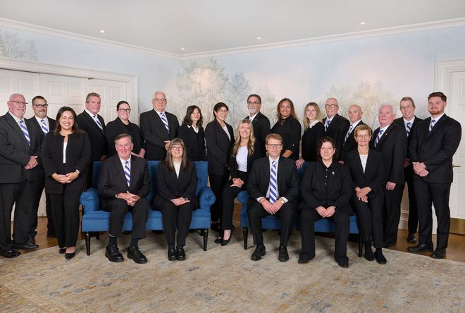 O'Donnell team posing in business attire indoors for a group photo.