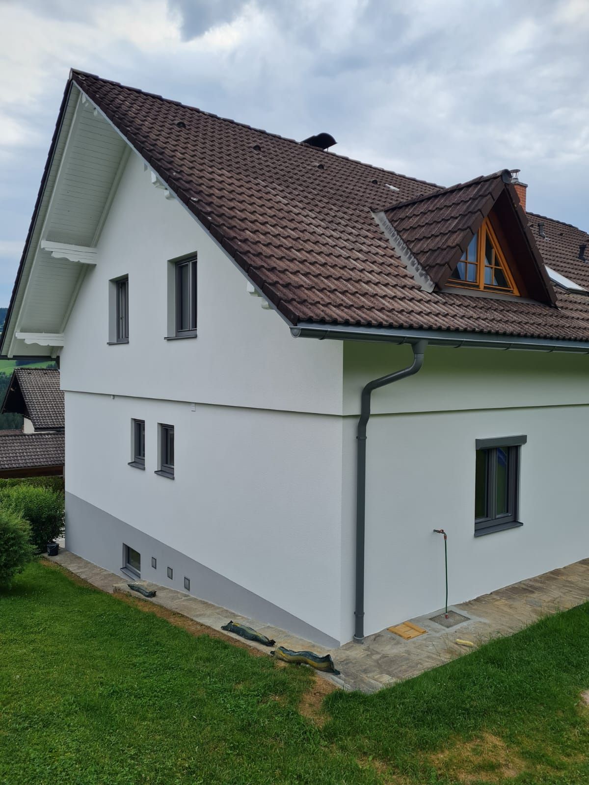 Auf einem üppig grünen Hügel steht ein weißes Haus mit braunem Dach.